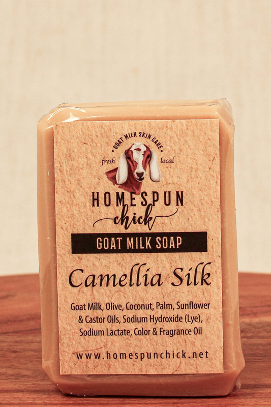 Goat milk soap bar with 'Homespun Chick' branding on a wooden surface.