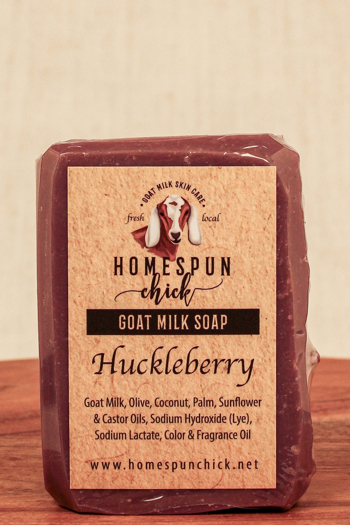 Bar of goat milk soap with 'Homespun Chick' label on a wooden surface