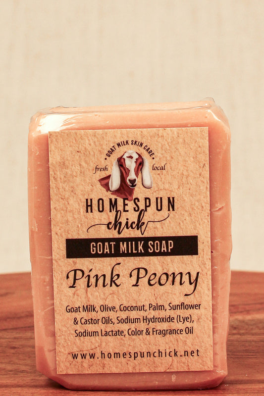 Pink goat milk soap bar with 'Homespun Chick' label on a wooden surface.