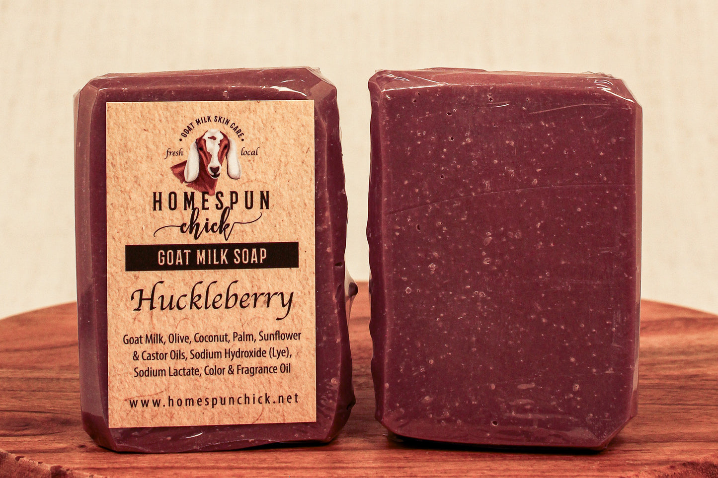Huckleberry goat milk soap with packaging on a wooden surface