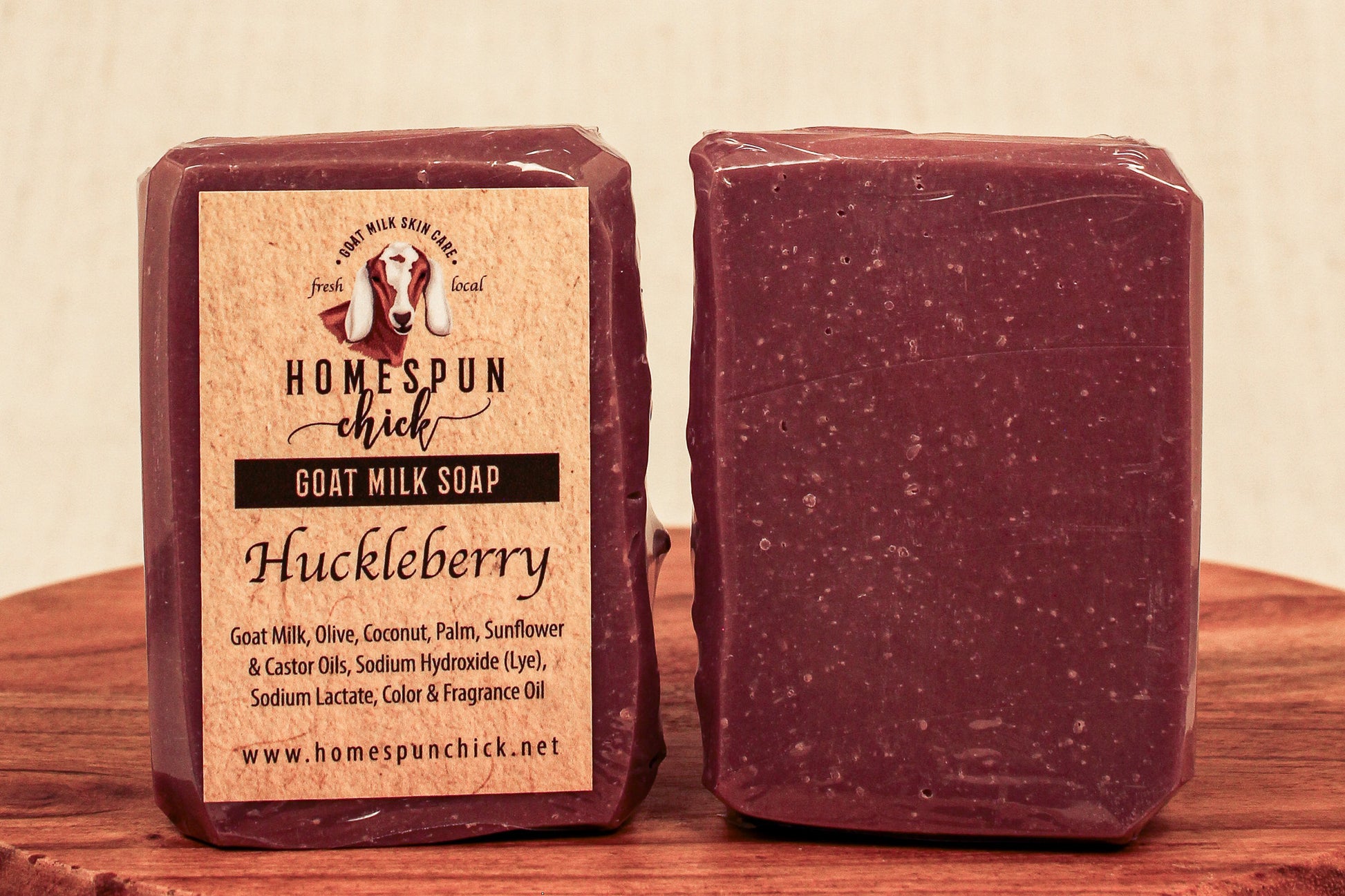 Huckleberry goat milk soap with packaging on a wooden surface