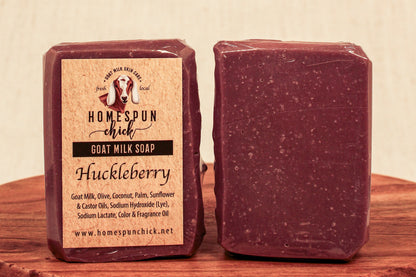 Huckleberry goat milk soap with packaging on a wooden surface