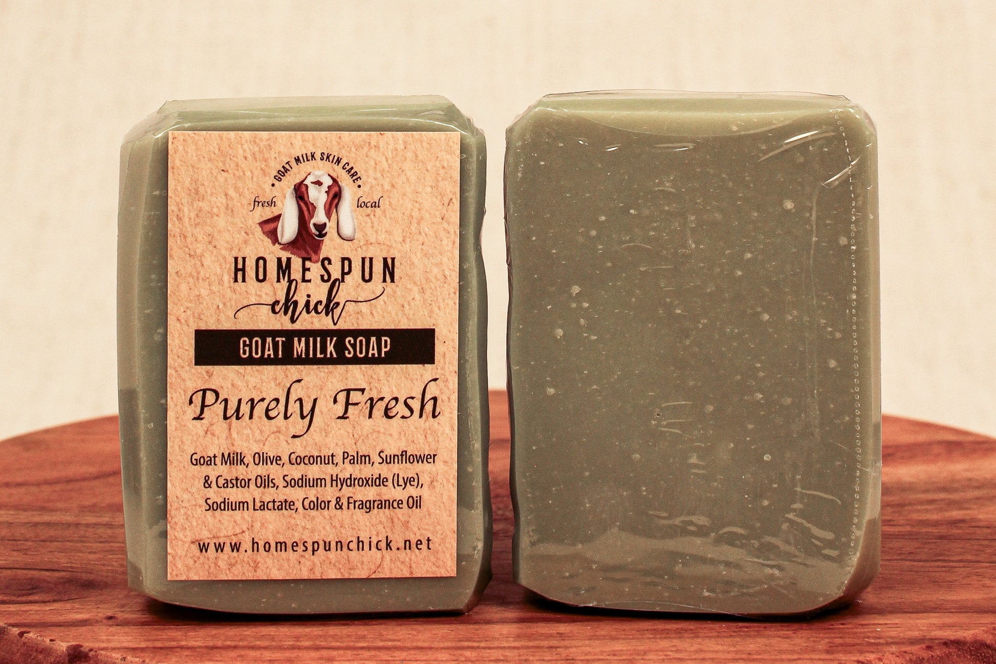 Two bars of goat milk soap with a visible label on a wooden surface.